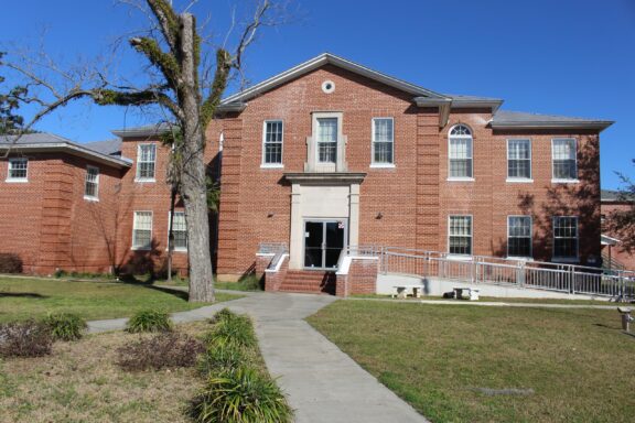 Brick Courthouse Building with White Columns and Stairs on a Sunny Day A view of the facade of the Liberty Courthouse in Bristol, Florida.
