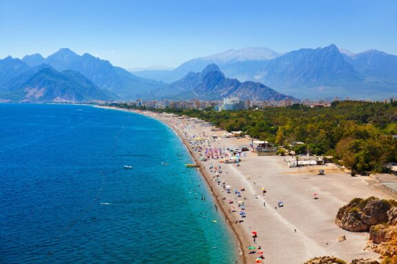 An aerial view of a beach in Antalya Turkey with mountains in the background.