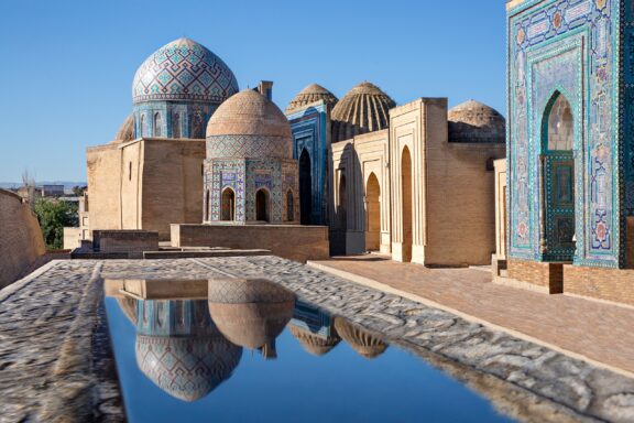 Buildings of the Shah-i-Zinda Necropolis are reflected in a small pool in Samarkand, Uzbekistan.