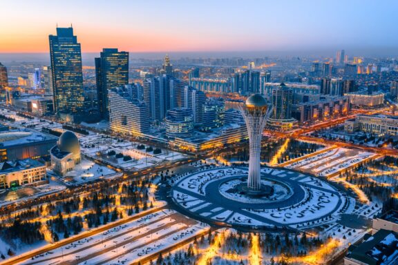 An aerial view of the Baiterek Monument surrounded by tall buildings in Astana, Kazakhstan.