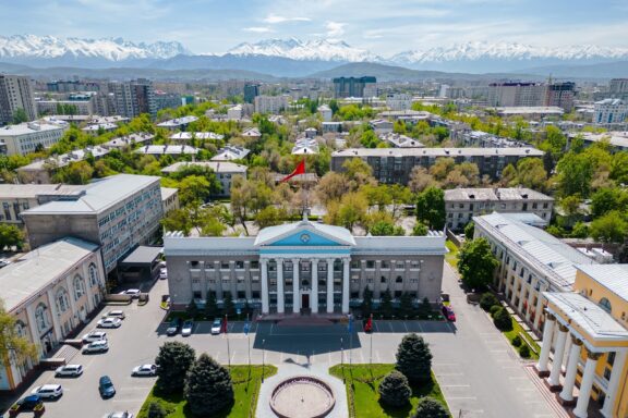 Bishkek Cityscape with Snow-Capped Mountains in the Background Aerial view of Bishkek, framed by the majestic Kyrgyz Ala-Too range