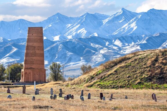 Burana Tower in Kyrgyzstan with Snow-Capped Mountains in the Background Burana Tower, a remnant from the ancient city of Balasagun