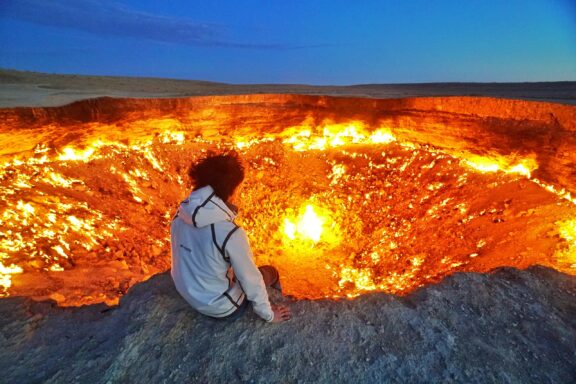 A person sits on the edge of the Darvaza Gas Crater in Turkmenistan.