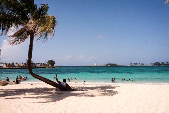 Tropical Beach with Palm Tree and Visitors Junkanoo Beach, named after the traditional Bahamian festival of Junkanoo