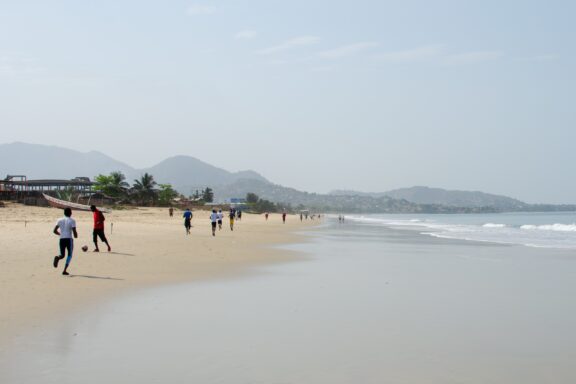 Beachgoers on Sandy Shoreline with Distant Mountains Lumley Beach, a place where locals congregate for sporting events and relaxation