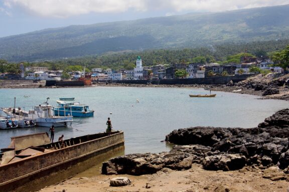 Coastal Town with Boats and Volcanic Rocks Moroni's skyline set against Ngazidja Island's volcanic mountains