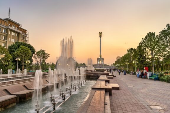 A view of a fountain leading to the Independence Monument in Dushanbe, Tajikistan at sunset.