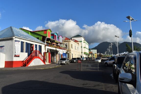 Colorful buildings lining a street in Roseau with mountains in the background The commercial area in Roseau, including modern cafes, historic shops, and essential government buildings