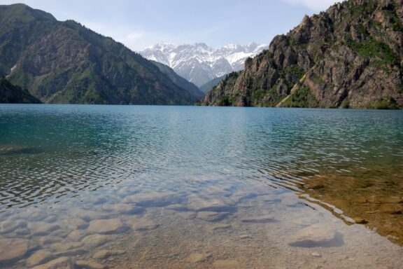 A view of a lake in the Sary-Chelek Biosphere Reserve with mountains in the background.