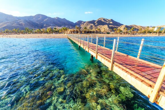 A dock extends over clear, turquoise waters at Eilat, Israel.