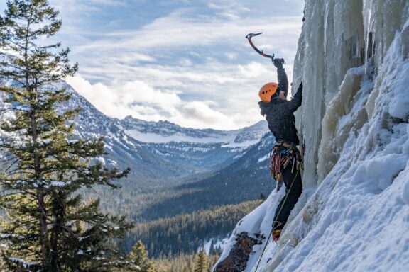 An ice climber climbs a frozen waterfall in Hyalite Canyon in winter.