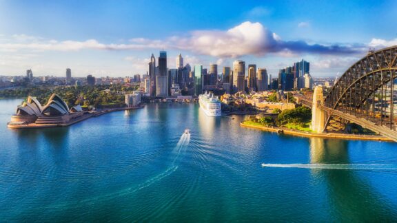 Panoramic View of Sydney Skyline with Opera House and Harbour Bridge, Australia The Sydney Opera Houe and the Sydney Harbour Bridge can be seen in an aerial view of the Sydney Harbour in Sydney, Australia.