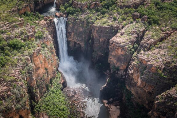Majestic Waterfall Cascading into a Gorge in the Northern Territory An aerial view of Jim Jim Falls during a sunny day in the Northern Territory.