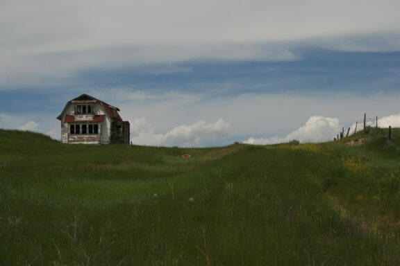 An abandoned farmhouse sits in a field of grass near Winnett in Petroleum County, Montana.