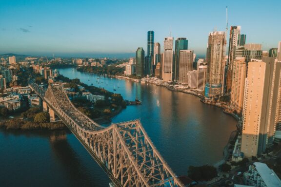 An aerial view of the Story Bridge spanning the Brisbane River at sunrise.