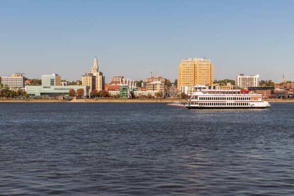 A view of the Celebration Belle Riverboat navigating the Mississippi River on a clear day.