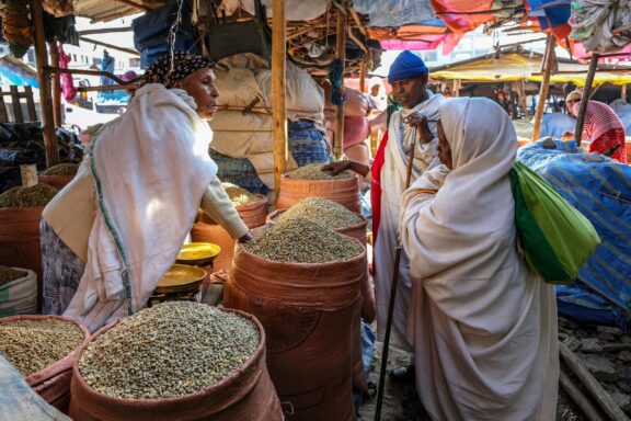 A woman sells coffee beans to customers in a market in Bahir Dar, Ethiopia.