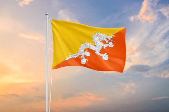 Bhutan's national flag waving against a soft sunset sky.