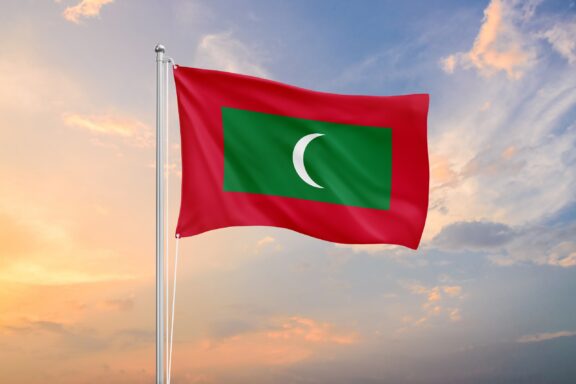 Flag of Maldives waving against a cloudy sky at dusk.