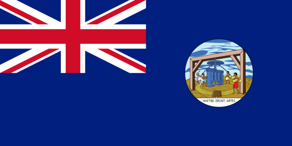 A historical colonial flag of Grenada with a Union Jack in the top left corner and a badge depicting a scene with people and a structure on the right side against a blue background.