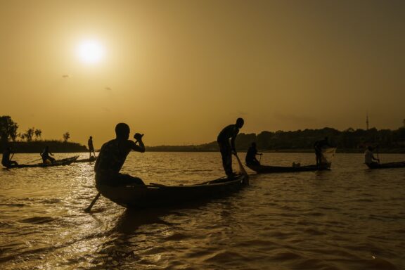 Silhouetted Figures on Boats at Sunset on the Niger River The Niger River, a chance to experience the waterway's natural splendor up close