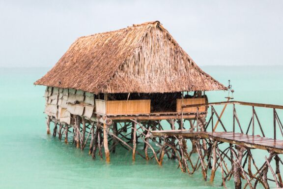 Traditional Stilt House Over Turquoise Lagoon Traditional thatched roof bungalow in the lagoons of South Tarawa