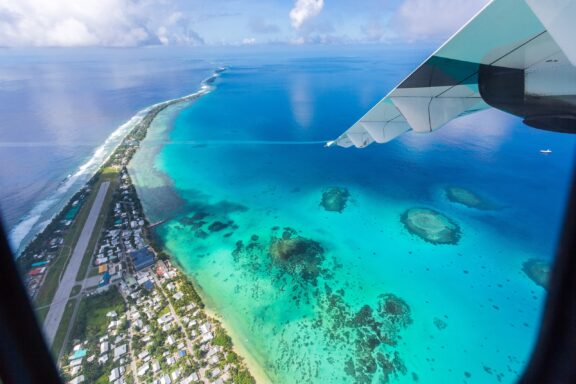 Aerial View of Funafuti Atoll, Tuvalu from Airplane Wing The landscape of Funafuti Atoll, showcasing its narrow land area and surrounding coral reefs