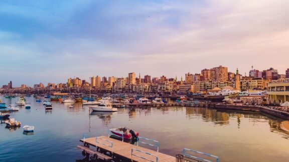 Boats sit in the water next to the coast in Alexandria, Egypt.