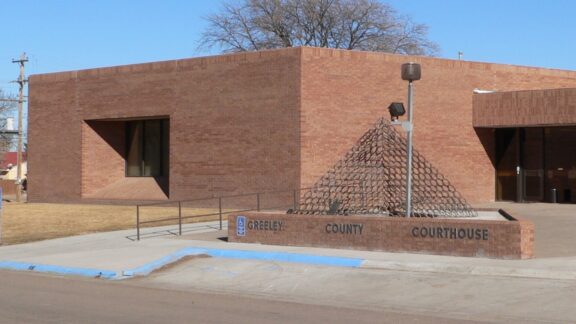 A street-level view of the entrance to the Greeley County Courthouse on a sunny day.