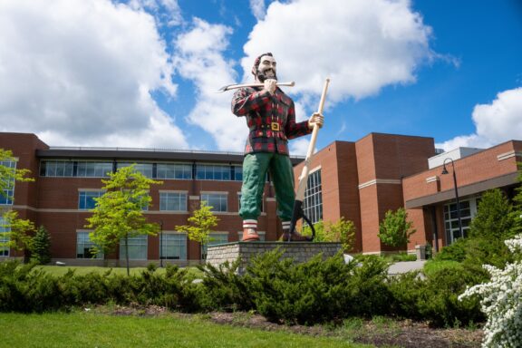 A low-angle view of a Paul Bunyan statue in Bangor, Maine on a sunny day.