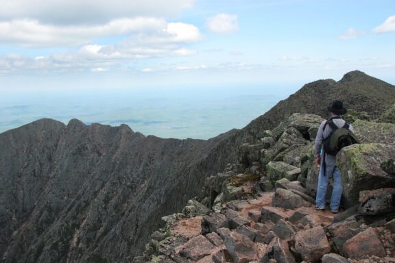 A man hikes Knife Edge Trail with sweeping views of Baxter State Park in Piscataquis County, Maine.