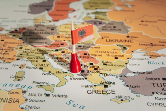 A pin with the flag of Albania placed on Tirana on a colorful map of Europe.