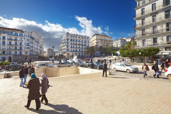 People and cars pass through a central street in Algiers, Algeria.