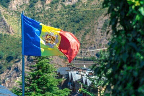 Flag of Andorra waving with a scenic mountainous background.