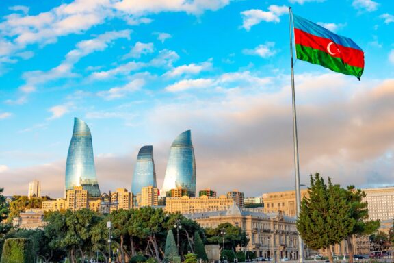 Azerbaijan flag waving in front of the Baku skyline with Flame Towers in the background.