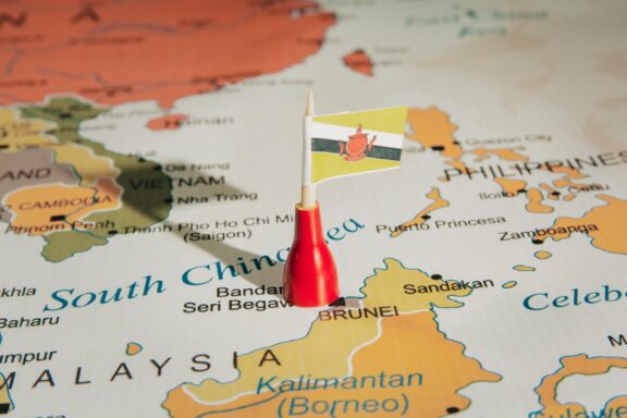 A Brunei flag pin placed on Brunei location on a colorful map.