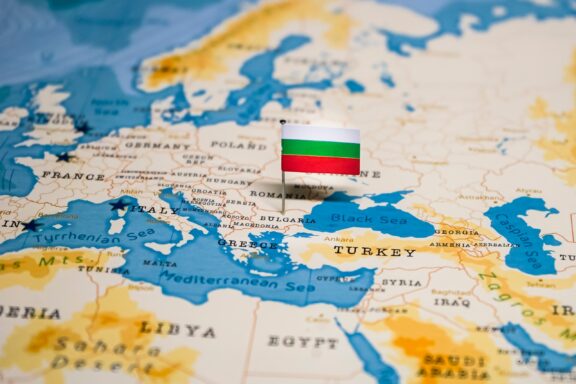 A pin with the flag of Bulgaria placed on a world map, indicating the country's location.