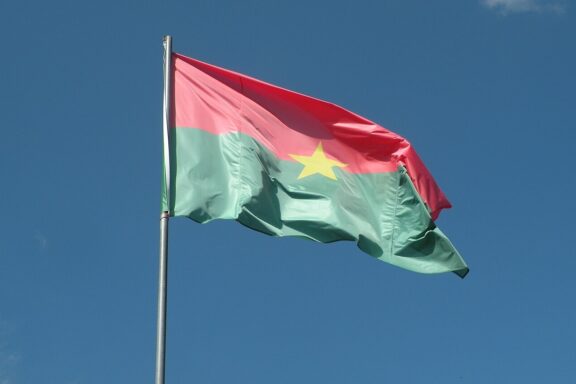 Flag of Burkina Faso waving against a clear blue sky.