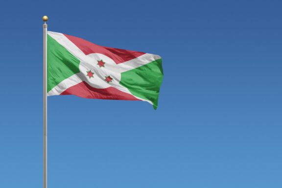 Flag of Burundi waving against a clear blue sky.