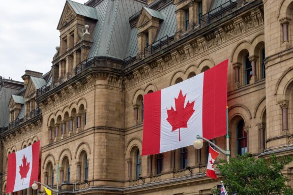 Canadian flag hanging on the side of a historic stone building in Ottawa.