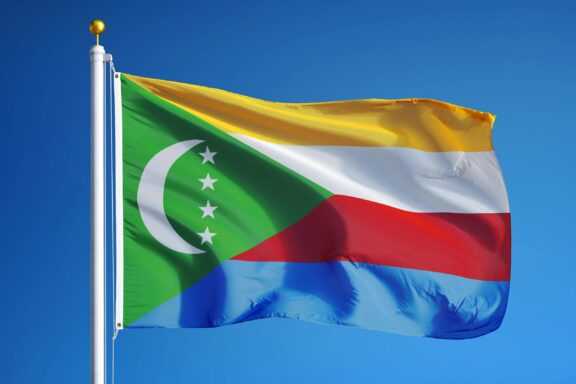 Flag of Comoros waving against a clear blue sky.