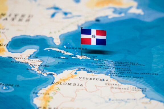 Dominican Republic flag pin placed on a map over the country's location.