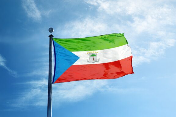 Flag of Equatorial Guinea waving against a clear blue sky.