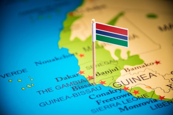 A pin with the flag of The Gambia placed on a map highlighting the country's location in Africa.