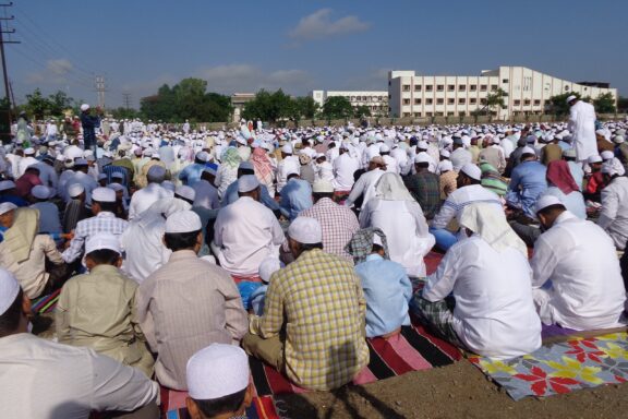 Many people sit and take part in prayer outside in Malegaon, India.