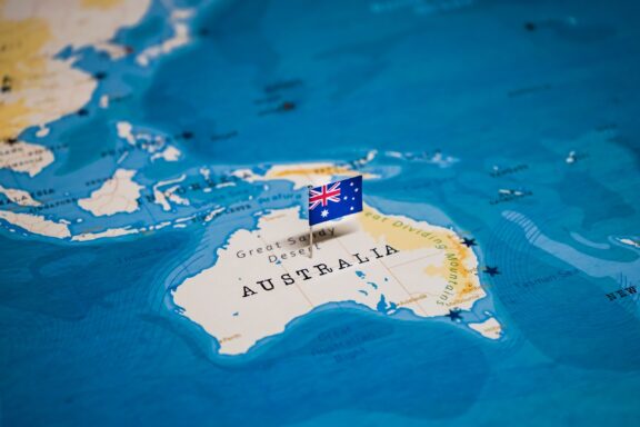 A pin with the Australian flag on a map highlighting the country of Australia.