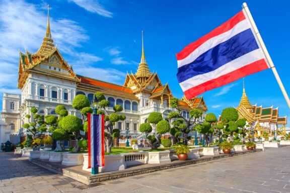 Grand Palace and Wat Phra Kaew with a large Thai flag in the foreground, Bangkok, Thailand.