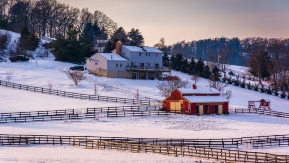 A view of a barn and house with snow covering in rural Carroll County, Maryland.