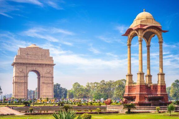 People gather around the India Gate in New Delhi, India on a sunny day.