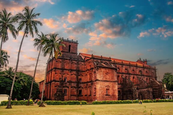 A low-angle view of the Basilica of Bom Jesus in Goa against a sunset sky.